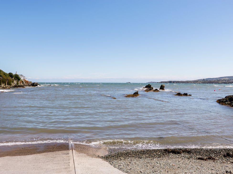 A coastal view with calm water rocks and a concrete ramp by the shore at Bay Lodge in Bull Bay