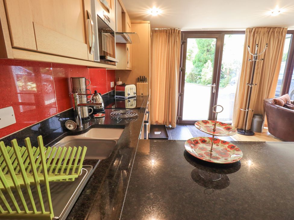 A kitchen with black countertops cabinets and red backsplash at Stonegarth Mews in Grasmere