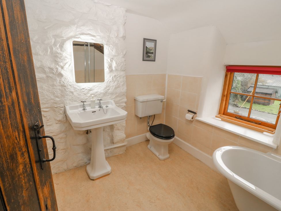 A bathroom with a sink mirror toilet bathtub and window at Peniarth Ganol in Tywyn
