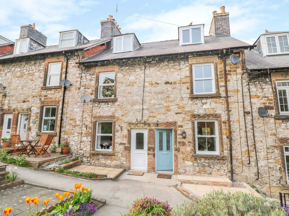 A stone row house with two front doors and flower beds in front at Wyebrow Cottage in Bakewell