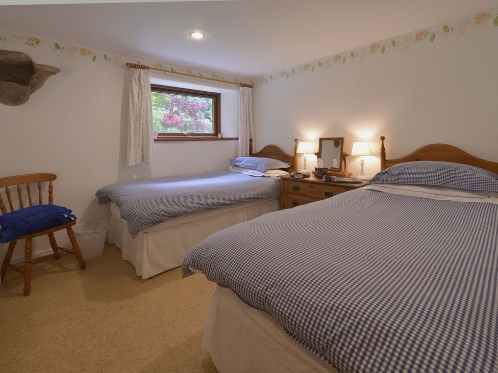 A bedroom with two single beds wooden chair and a wooden dresser with lamps at Water Barn in Manaton near Lustleigh