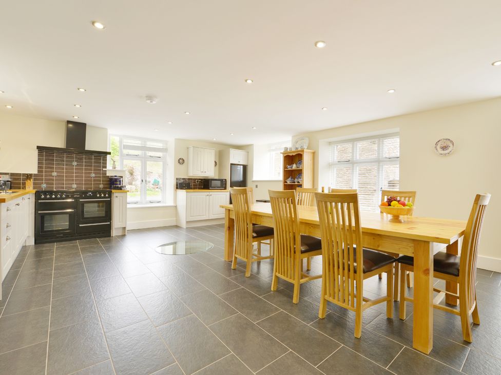 A kitchen and dining area with a wooden table and chairs and a stove at The Cider Barn at Home Farm in Down Thomas near Plymouth