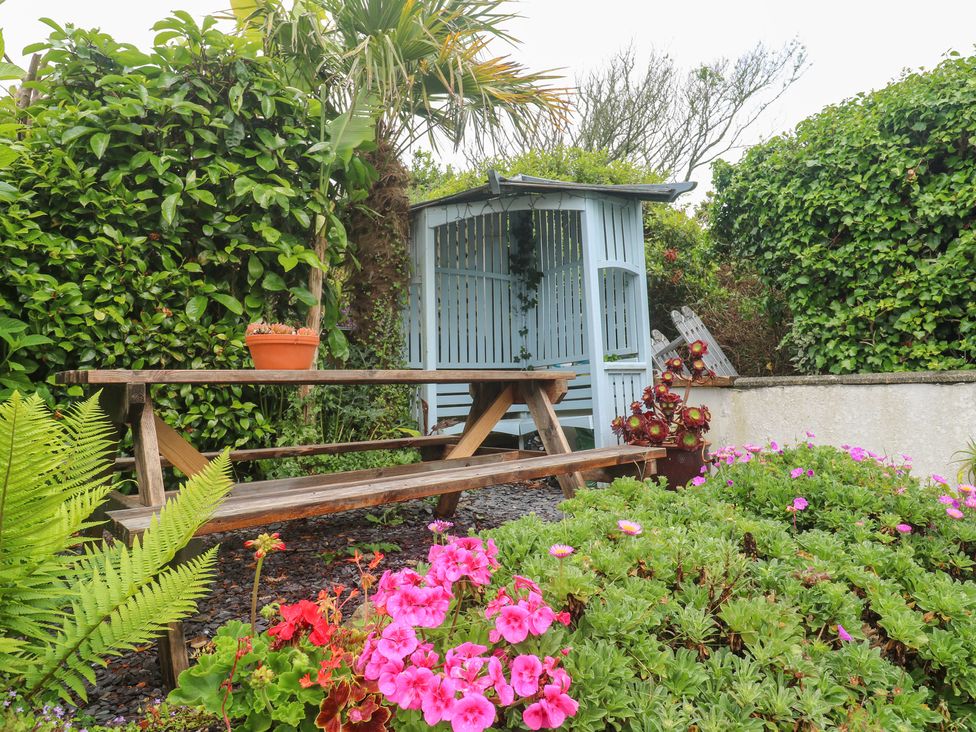 A garden with a bench and flowers at 2 The Cottages, Ludgvan