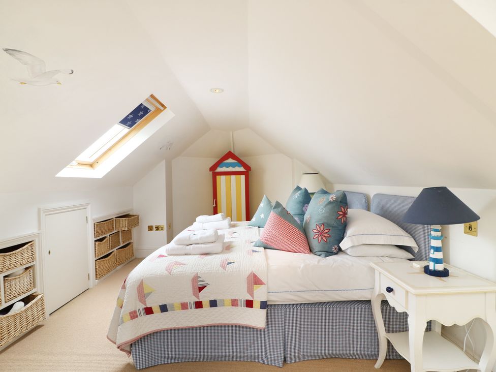 A bedroom with a bed pillows bedside table lamp baskets under a skylight at Elphinstone in Newton Ferrers near Plymouth