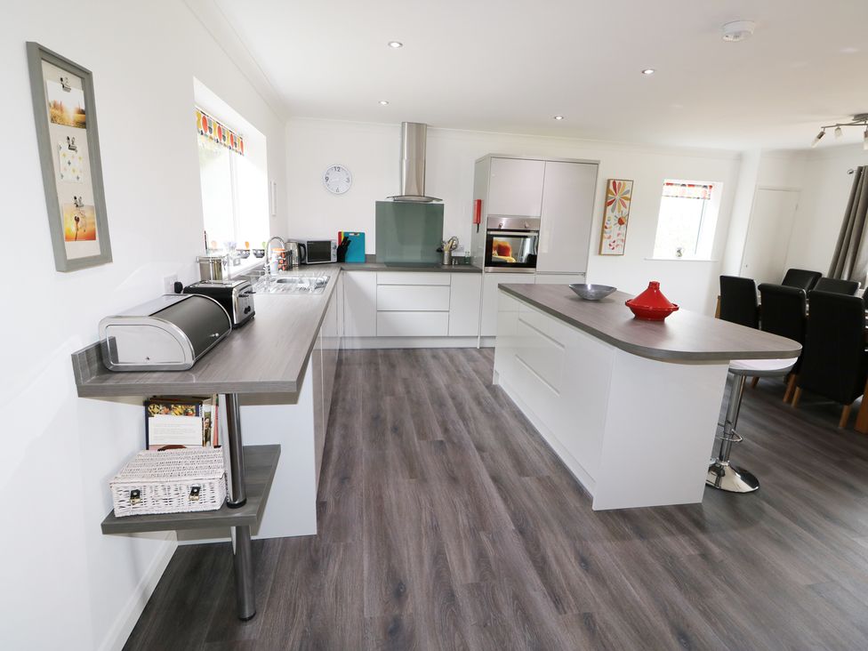 A modern kitchen with an island and dining area at Heron Lodge in Mavis Enderby near Spilsby