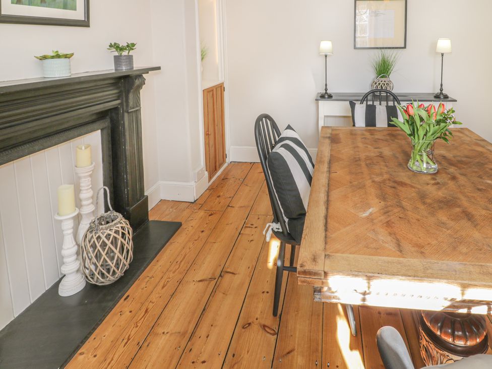 A dining room with a wooden table and black chairs with striped cushions at Bwthyn Morse in Llanfair