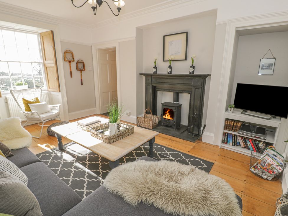 A living room with a fireplace a television and a window with wooden shutters at Bwthyn Morse in Llanfair