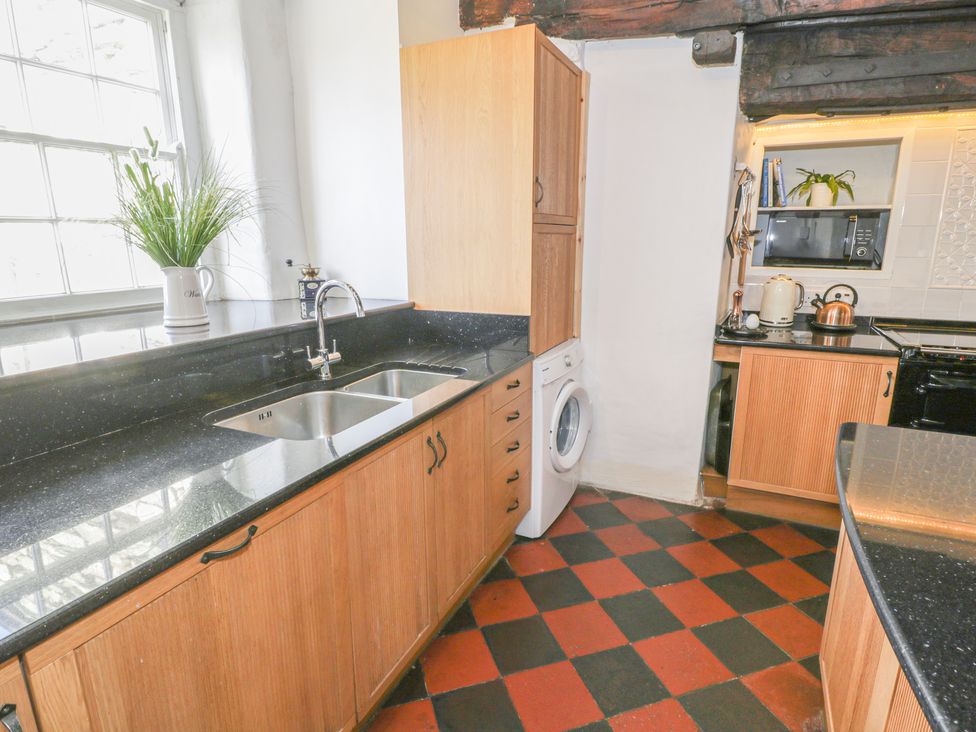 A kitchen with a black countertop sink washing machine kettle and microwave at Bwthyn Morse in Llanfair