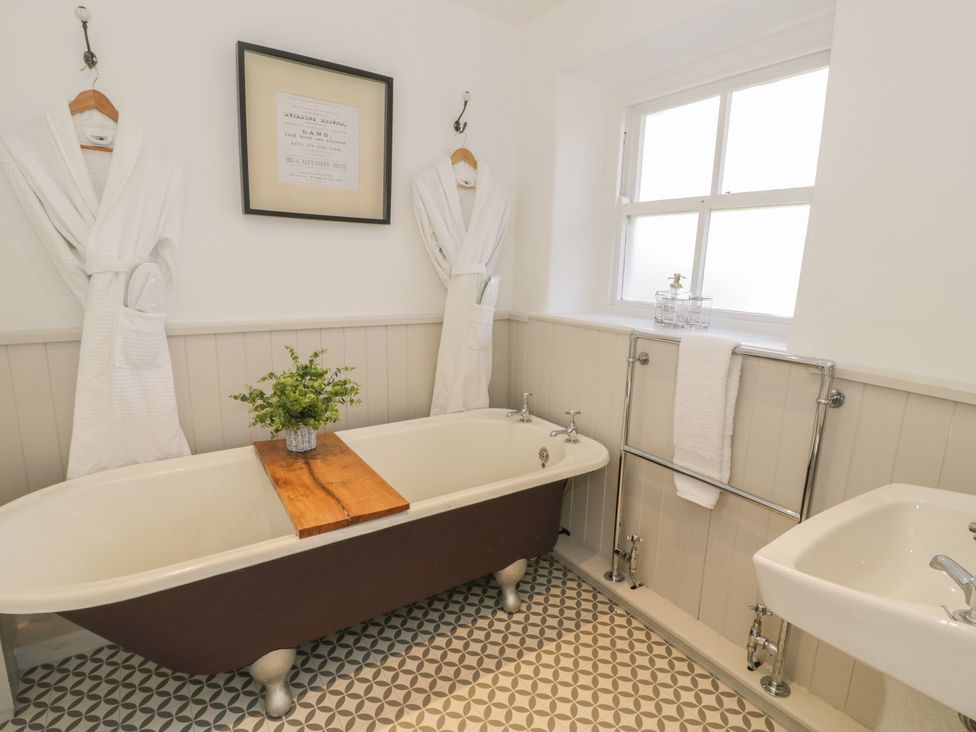 A bathroom with a clawfoot bathtub and two white robes hanging on the wall at Bwthyn Morse in Llanfair