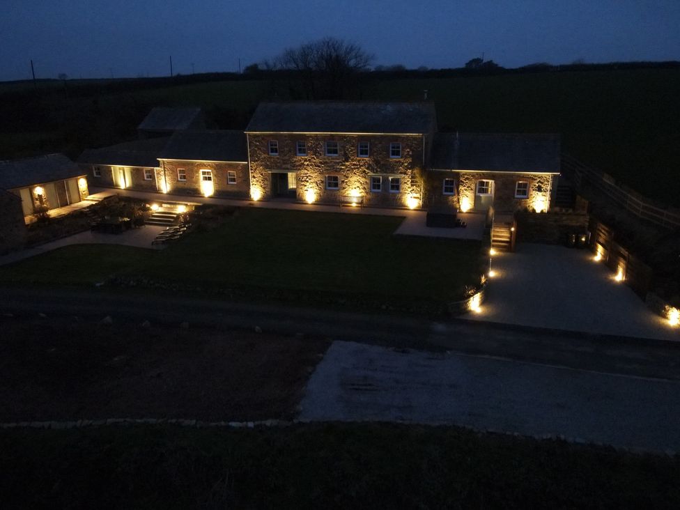 A stone house with exterior lights along the walls and driveway at Silvermine House in Charlestown