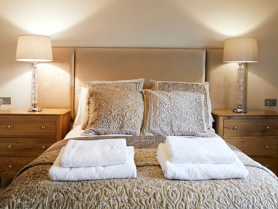A bed with folded towels on a quilted bedspread and pillows with two bedside tables and lamps at Holly Edge in Moorsholm