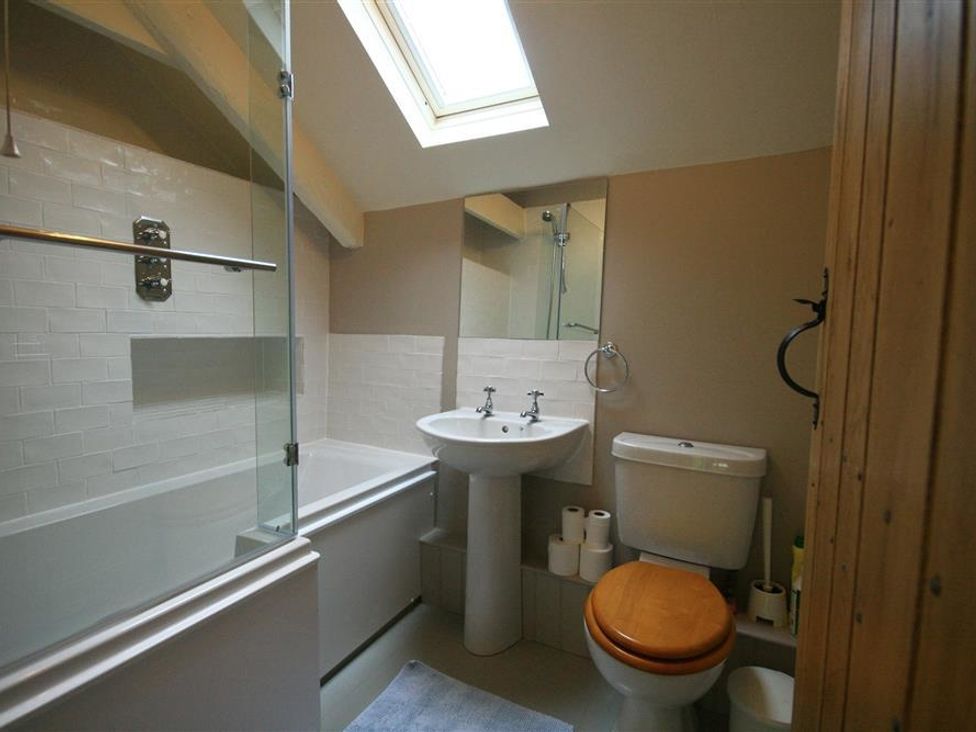 A bathroom with a bathtub shower combination sink toilet and skylight at Cider Press Cottage in Priston Village Bath