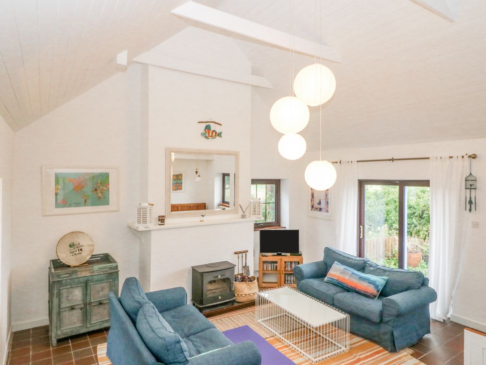 A living room with two blue sofas a white coffee table a fireplace and hanging lights at The Schooner in Goleen County Cork