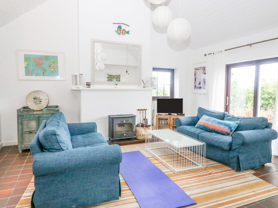 A living room with two blue sofas a white coffee table a wood stove a television and a yoga mat at The Schooner in Goleen County Cork
