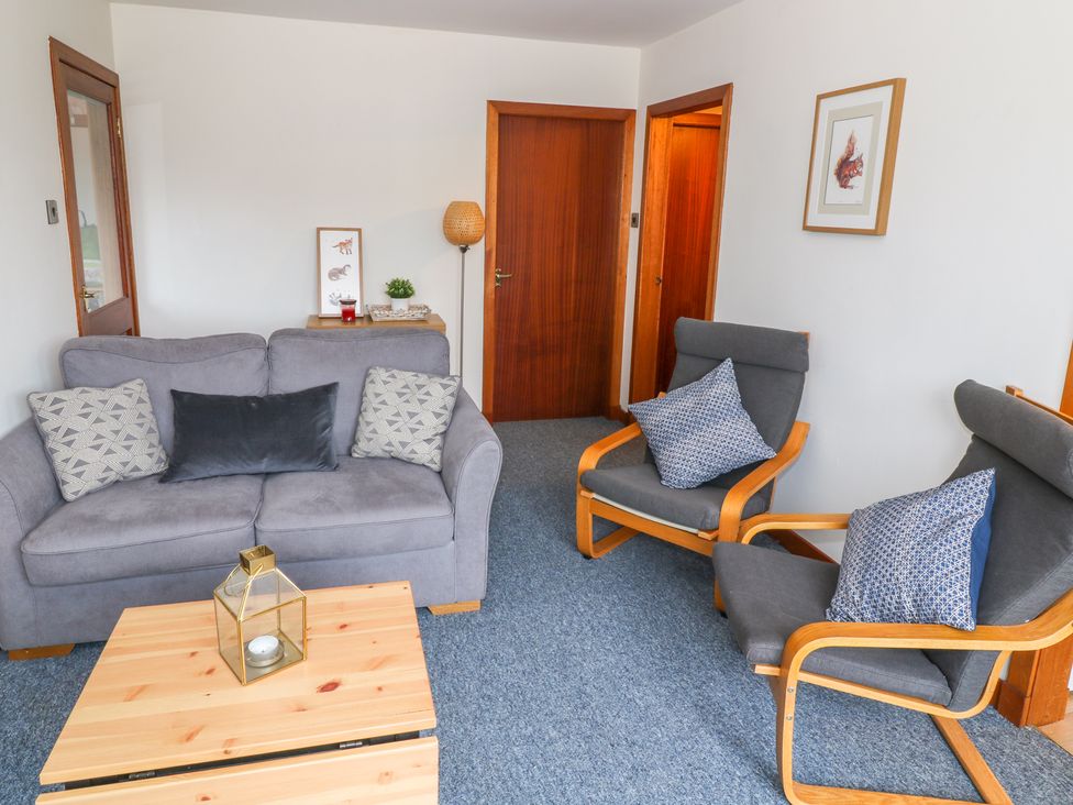 A sitting room with a gray sofa and two armchairs with cushions at Kestrel Lodge in Dumfries