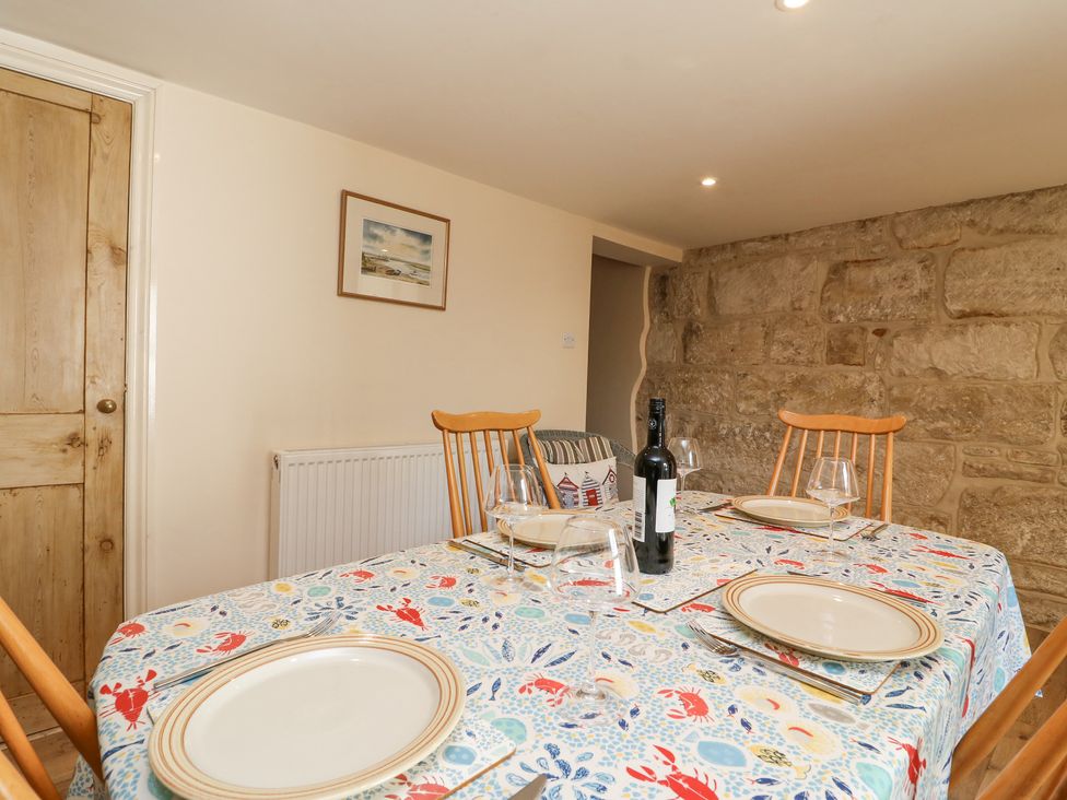 A dining room with a table set for four with plates wine glasses and a bottle of wine Bowmans Cottage Wakeham Portland