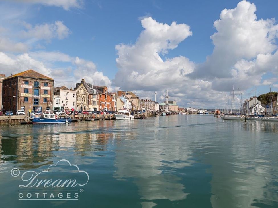 A harbor with boats docked and buildings lining the waterfront at Old Coastguard Apartment 3 in Weymouth
