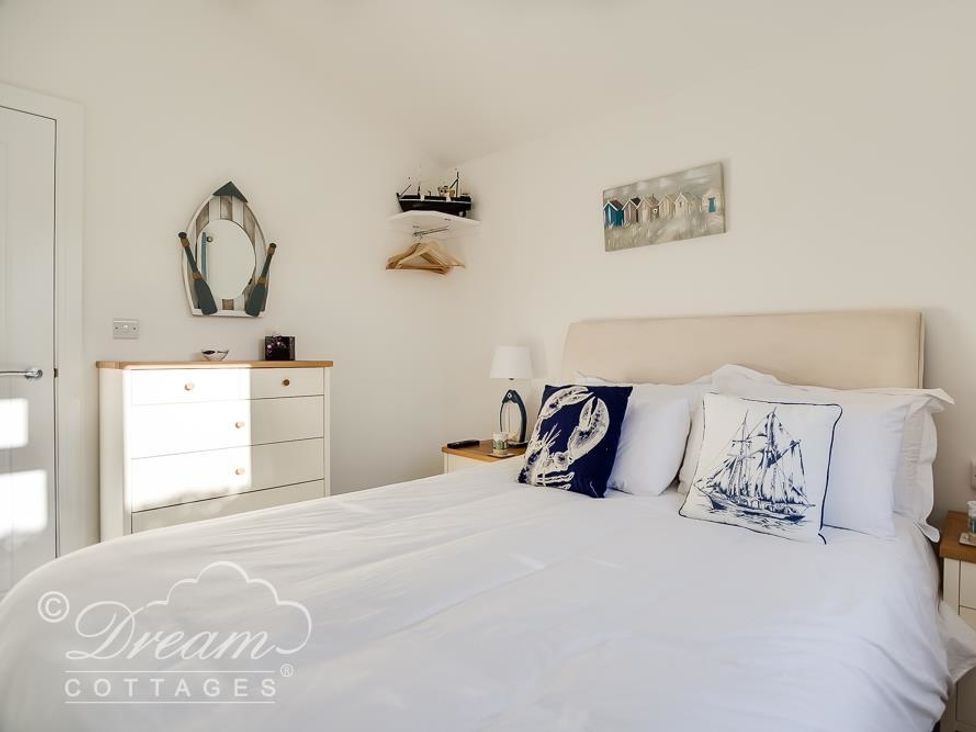 A bedroom with a double bed white bedding chest of drawers and nautical themed decorations at Outlook Lodge in Bowleaze