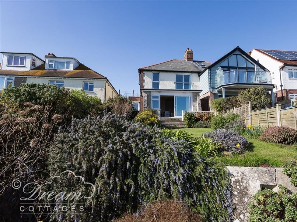 A backyard garden with bushes and grass behind two houses at Rainbows End in Cove Castle
