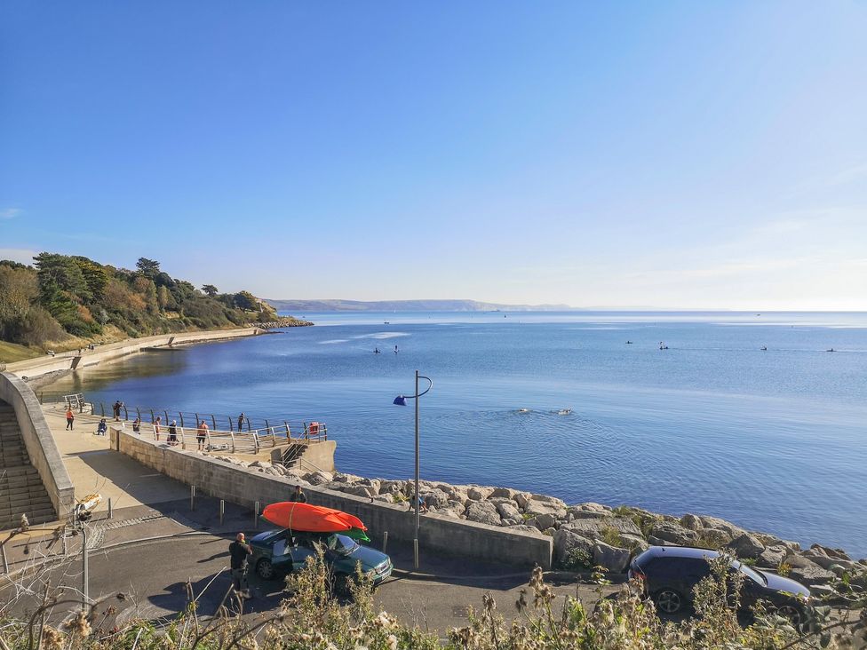 A coastal walkway with people near a sea wall and kayaks on a car at Reaver Brewers Quay harbour