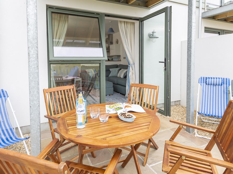 An outdoor patio with a round wooden table and chairs next to a glass door leading to a living room at 3 Ocean Reach in Bolberry
