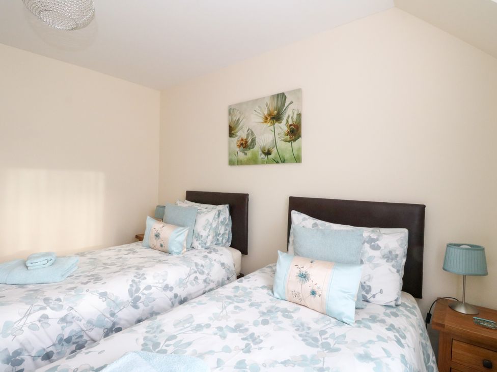 A bedroom with two single beds floral bedding and a bedside table with a lamp at 6 Aonachan Gardens Spean Bridge near Fort William