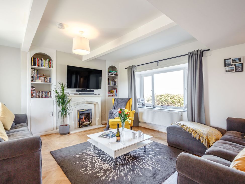 A living room with sofas coffee table TV fireplace and window at Tyn Y Berth in Benllech