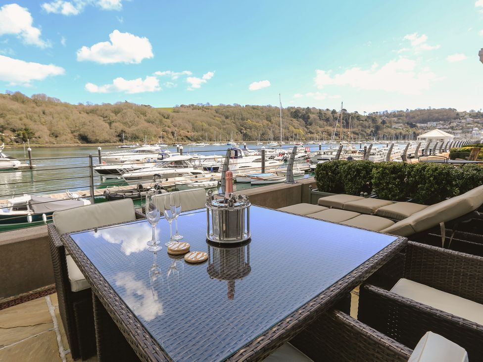 Outdoor patio with a table set with wine glasses and a champagne bucket overlooking boats at Quayside Dart Marina in Dartmouth