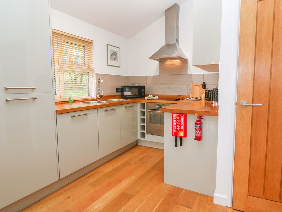 A kitchen with wooden floors and countertops a microwave a knife block a fire extinguisher and a fire blanket at 1 Lake View Lanreath