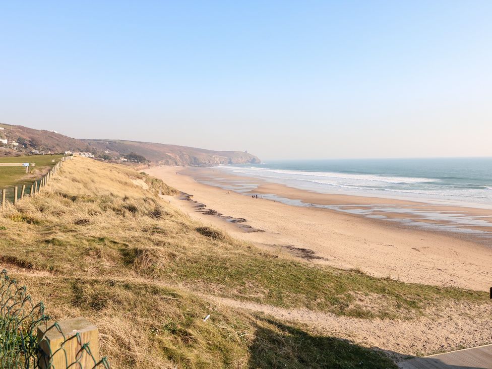 A sandy beach with waves and grassy dunes alongside a fence at Praa Waves in Praa Sands